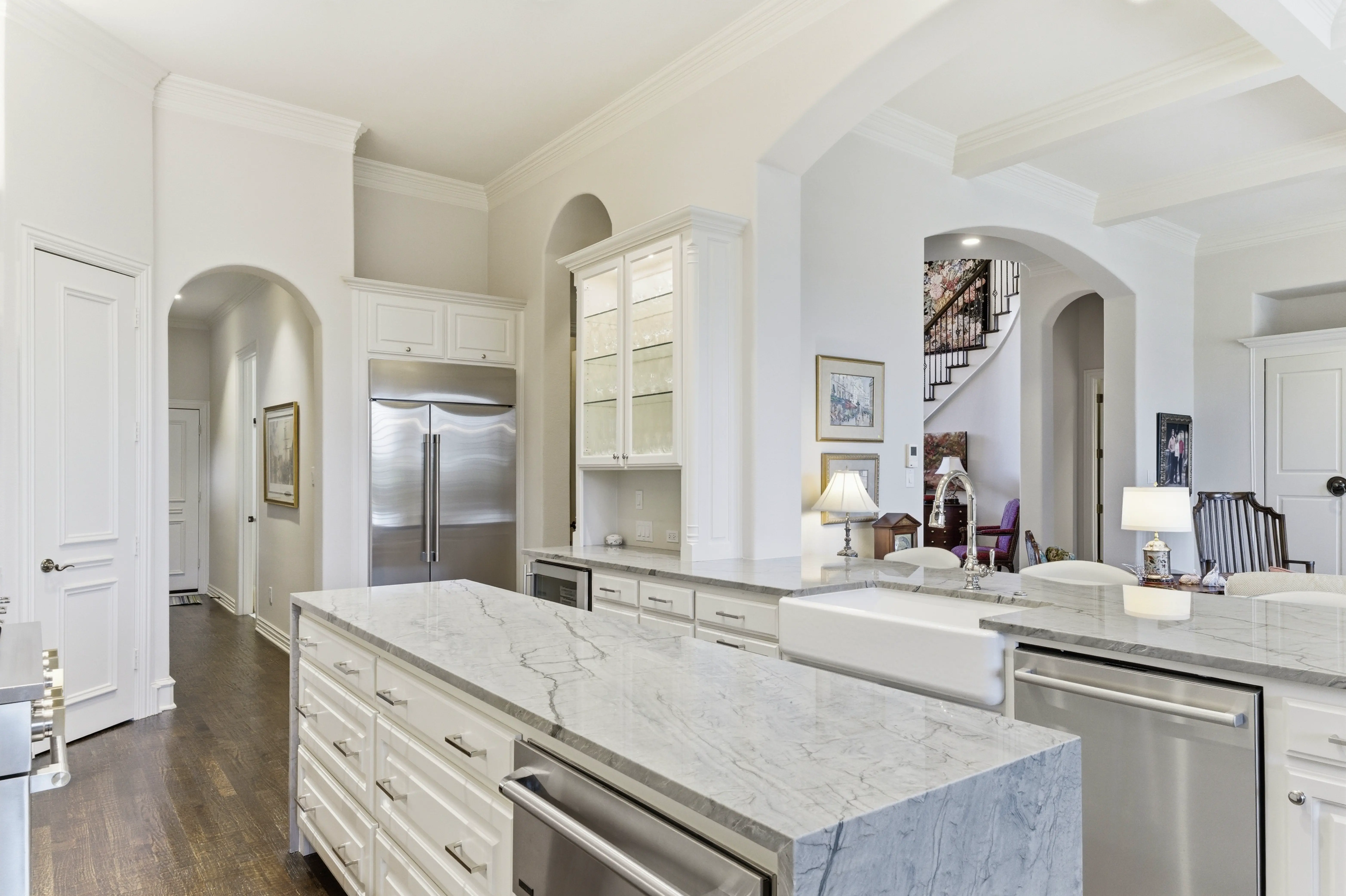 Quartzite waterfall island with drawers and farmhouse sink, architectural archways to living area